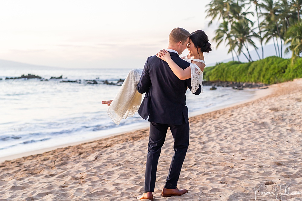 groom carrying bride on the sand 