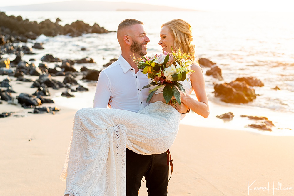 groom carrying bride on a Maui beach 