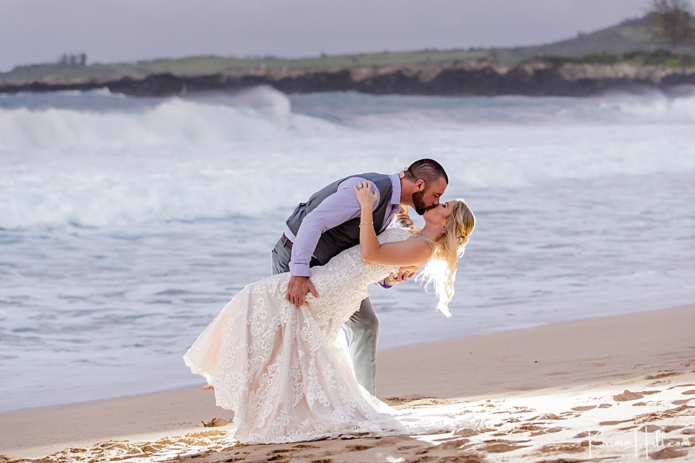 bride and groom kissing with waves crashing in the background - best wedding packages on Maui 