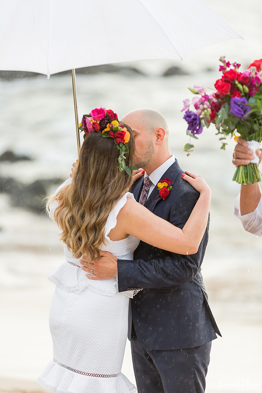bride and groom kiss under an umbrella on a maui beach 