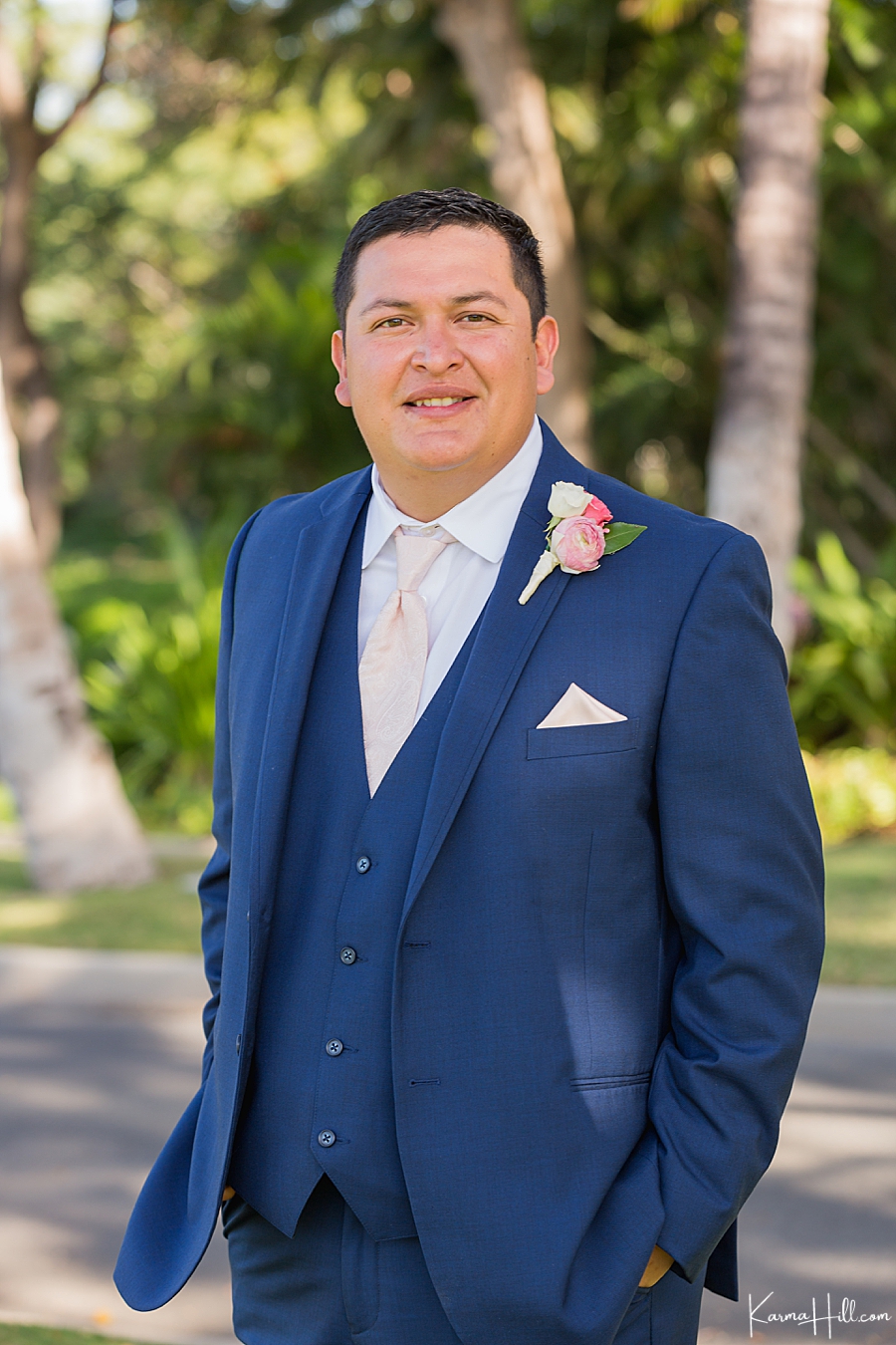 groom in hawaii wearing dark blue suit and pearl pink tie with matching boutonniere 