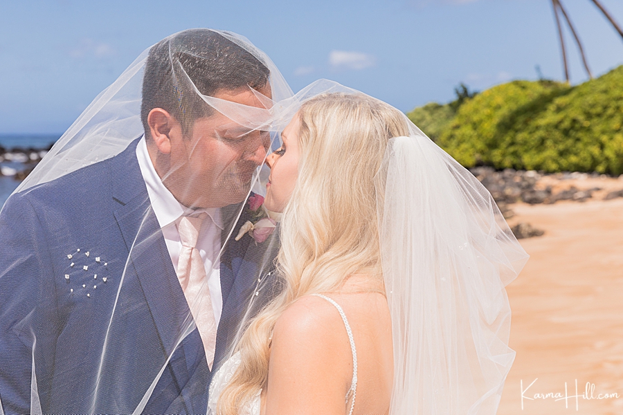 bride and groom kiss under veil in maui beach 