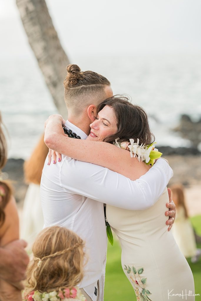 bride celebrates her maui wedding by hugging adult son 