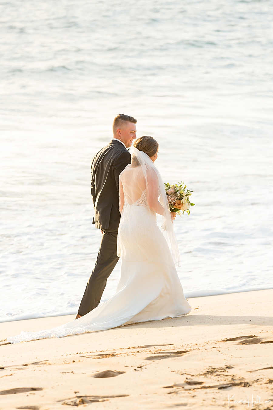 bride and groom walk on maui beach after their wedding 