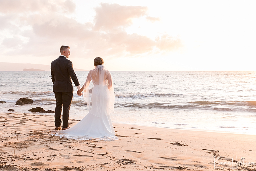 bride and groom on a maui beach watch the sunset 