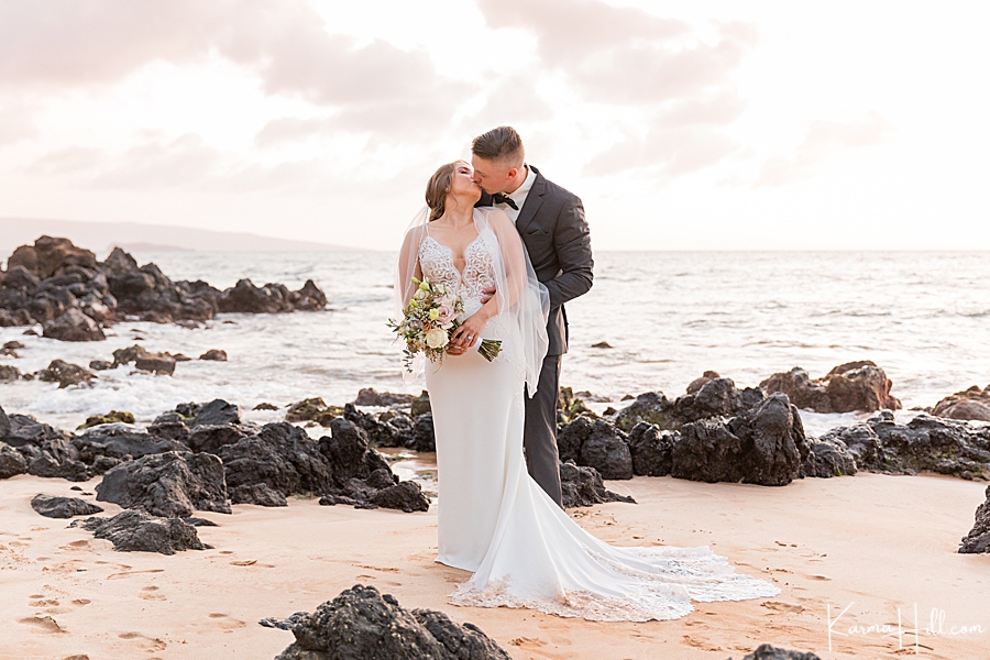 bride and groom kiss on a rocky beach in hawaii 