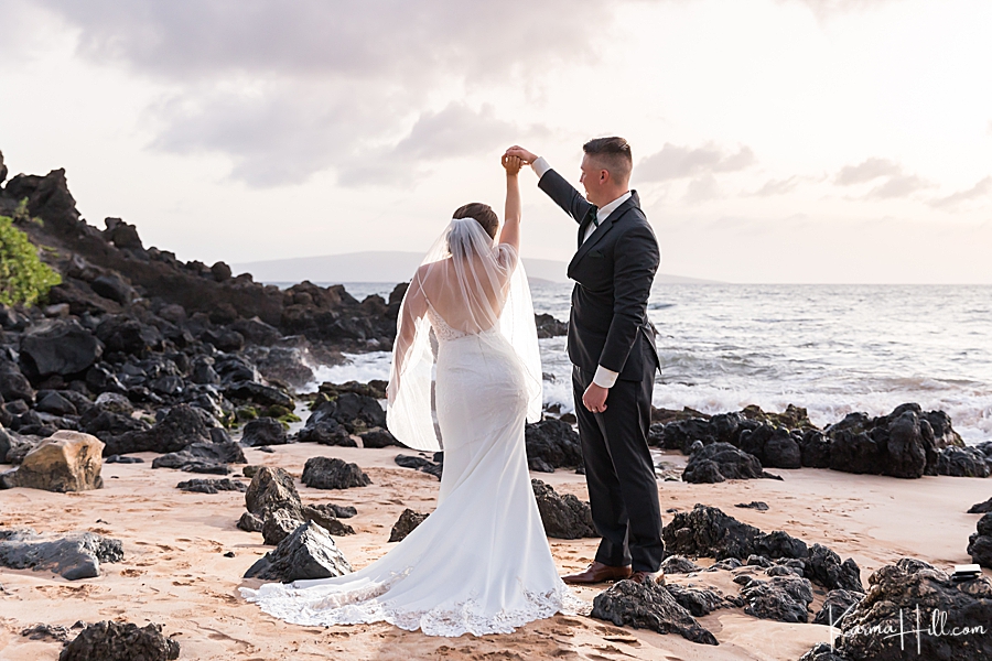 groom twirls bride on a rocky beach in hawaii 