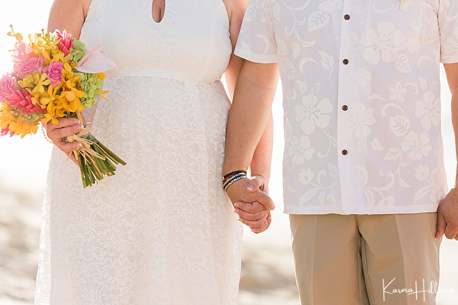 close up of bride and groom holding hands during their beach wedding 