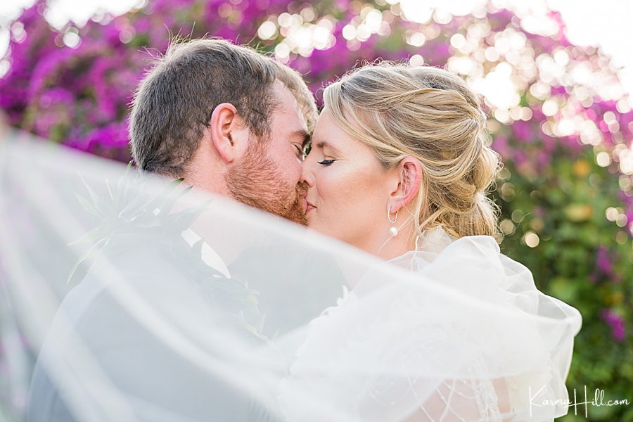 bride and groom kiss with veil flowing in the foreground 