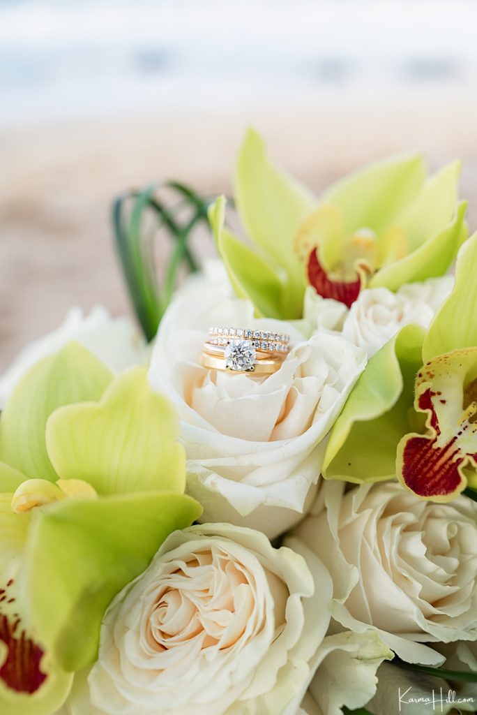closeup of rose gold rings with diamonds on a bridal bouquet of white roses and orchids 