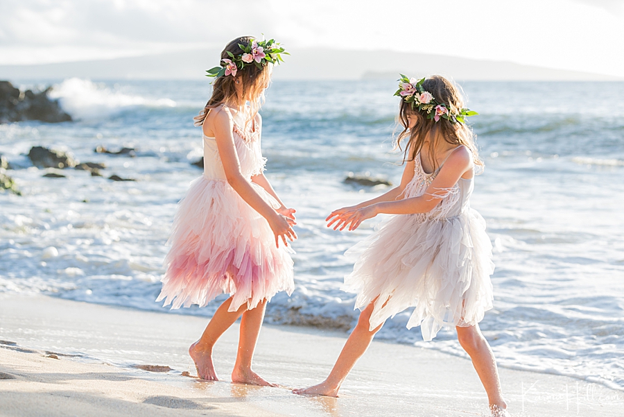 sisters playing in the water on maui beach while wearing wedding clothing 