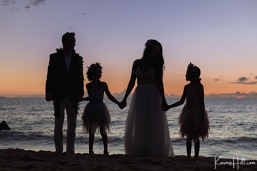 family in hawaii after wedding silhouetted in black against the sunset 