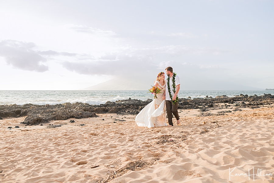 newly weds walk over the sand on maui beach 