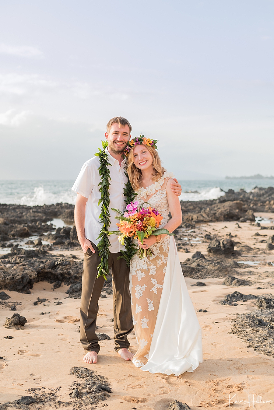 bride in wedding dress and groom in slacks and button down pose for their wedding photography on maui beach 