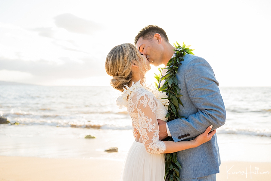 couple kisses in front of the sunset after their wedding in maui 