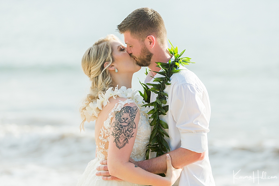 bride and groom kiss during their maui wedding on a beach 