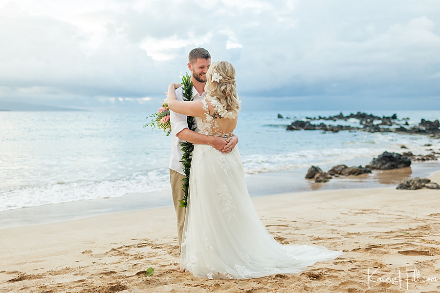 bride and groom have their first dance in front of hawaii ocean on the beach 