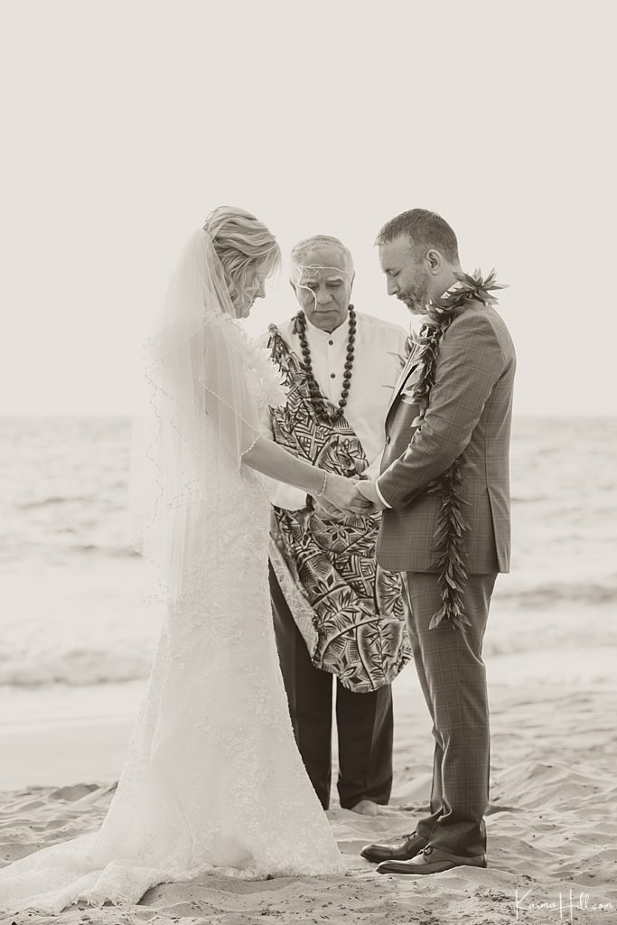 husband and wife pray during wedding on the beach 