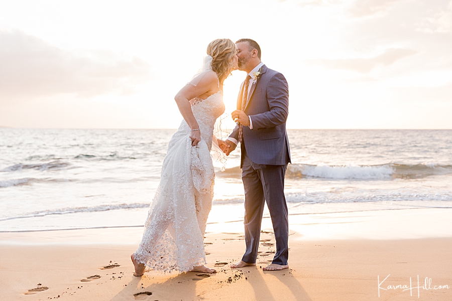 newlywed couple kiss on a hawaii beach in wedding dress 