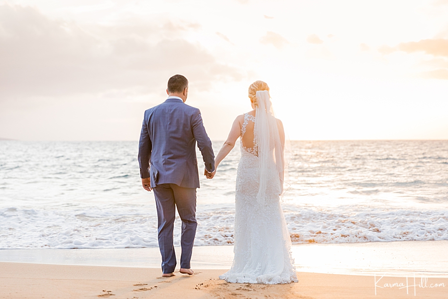 newly weds hold hands for hawaii sunset 