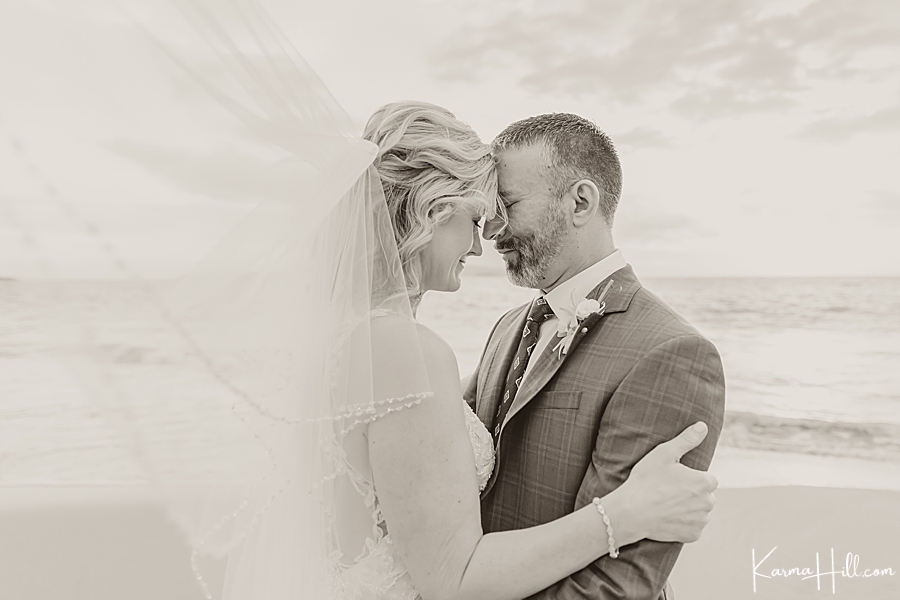 black and white photo of a bride and groom on their wedding day on a beach 