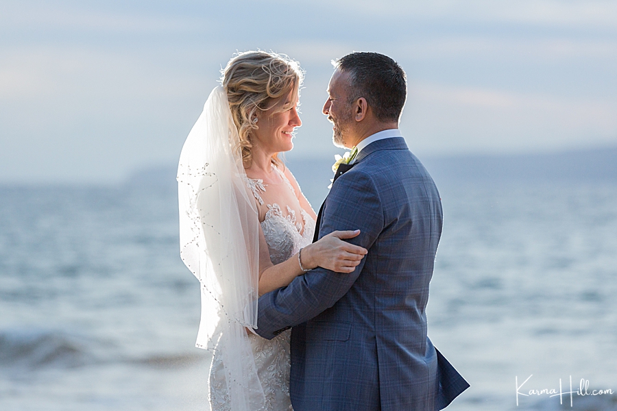 bride and groom gaze lovingly into each others eyes on a beach 