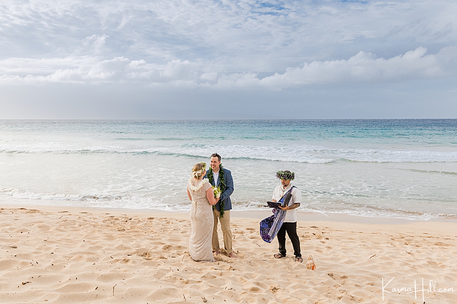real hawaii wedding on a maui beach with groom in a blue and beige suit and hawaiian minister in a haku lei 