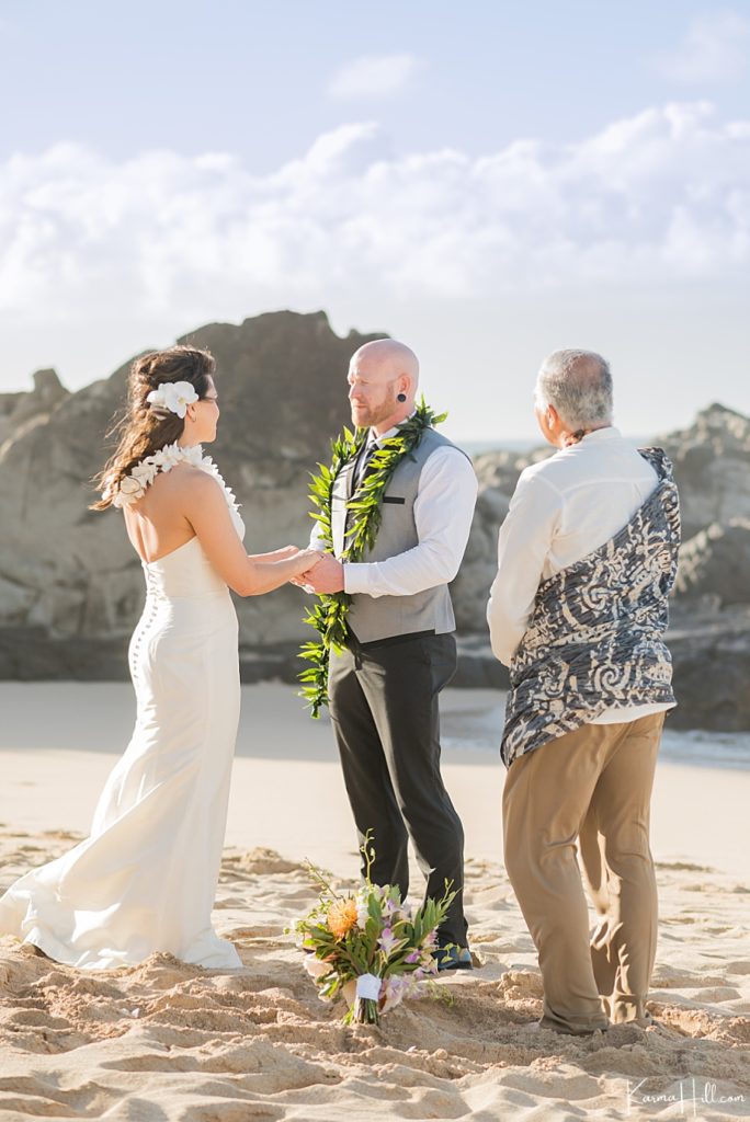 groom in grey vest with bride on beach in hawaii 