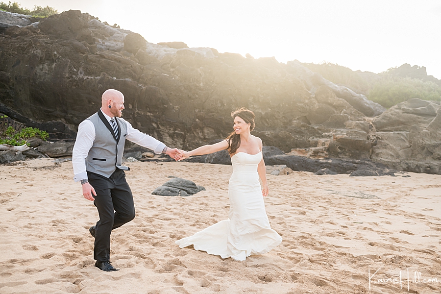 husband and wife hold hands on maui beach after getting married 
