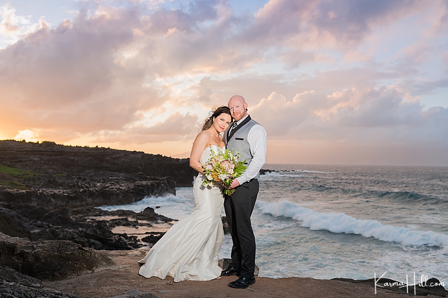 bride and groom pose in front of sunset on maui 