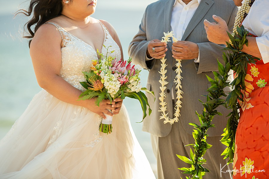 groom holds a tuberose lei to give bride during hawaii elopement 