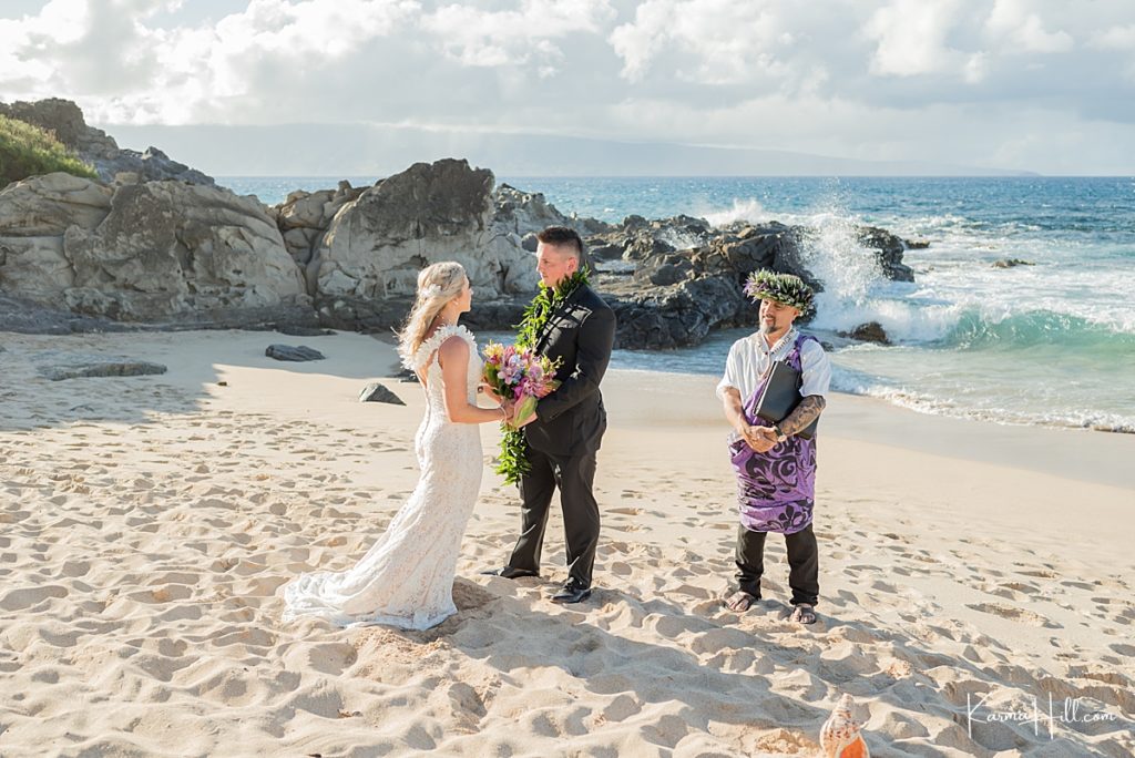 bride wearing a white mermaid gown, groom in black tux, and hawaiian minister in a purple wrap during a wedding in hawaii 