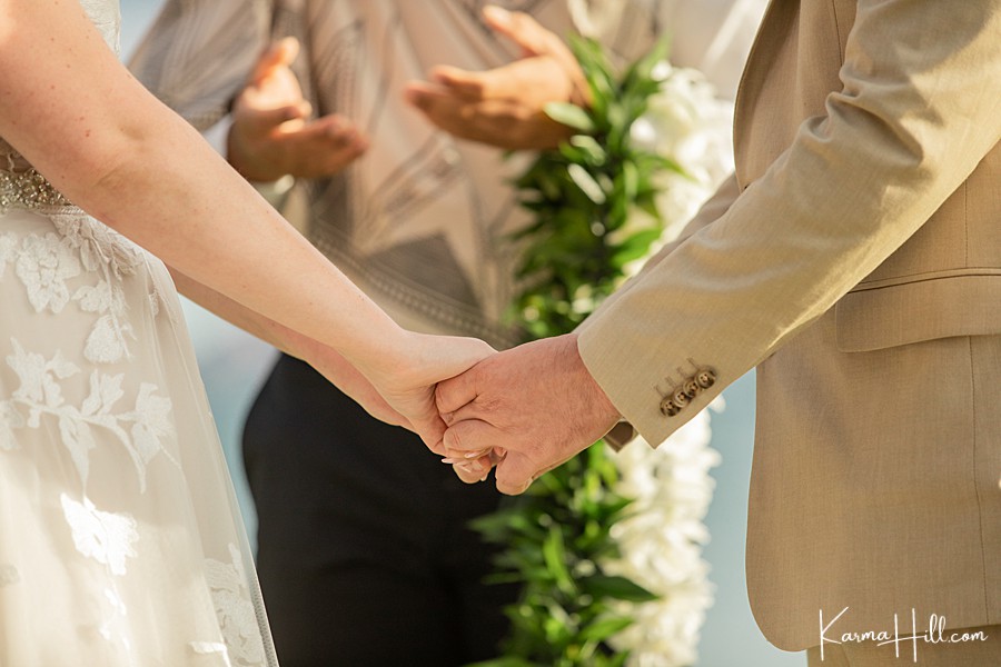 close up of bride and groom holding hands during their hawaii wedding 