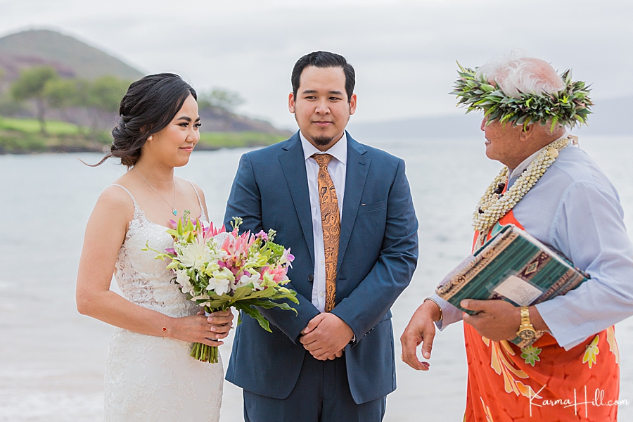 couple talk with hawaiian minister during their beach weddding 
