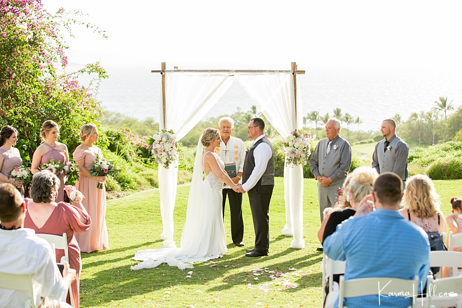 bride and groom hold hands in front of arch on maui 