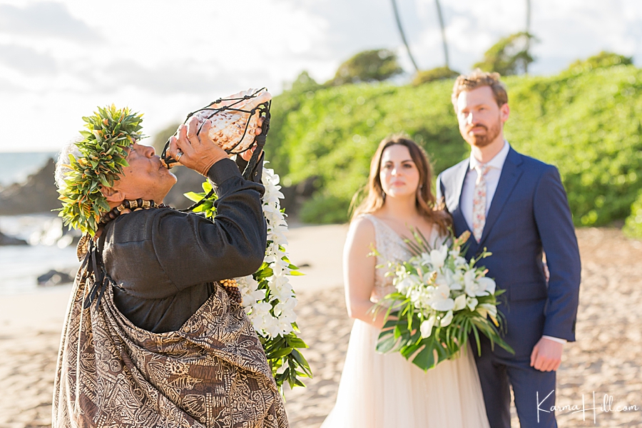 hawaiian minister blows the conch shell during a maui wedding 