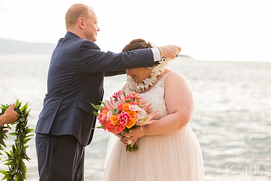 groom gives bride a lei for their maui beach wedding 