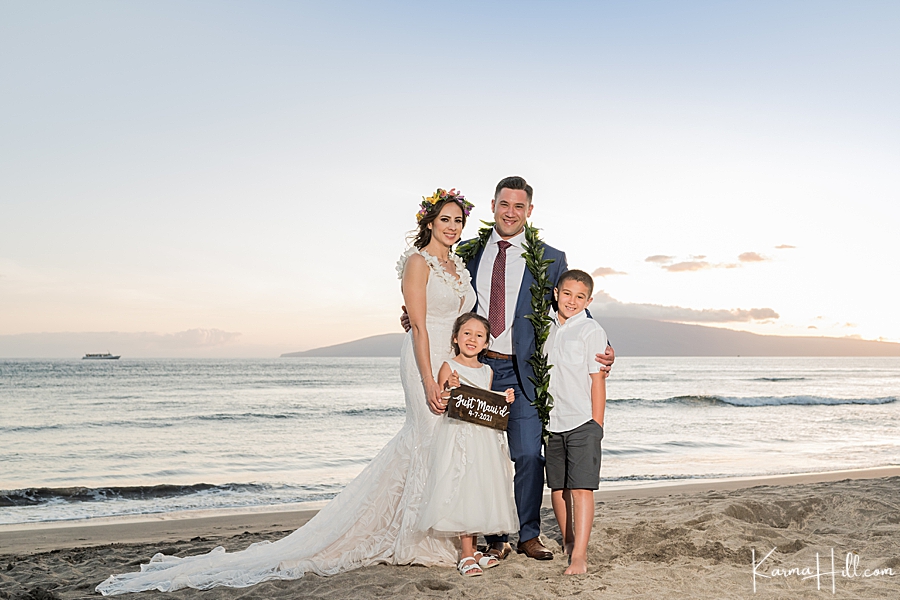 family pose with just maui'd sign on a maui beach 