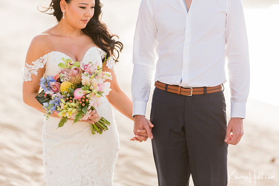 bride and groom hold hands on a maui beach during their wedding 