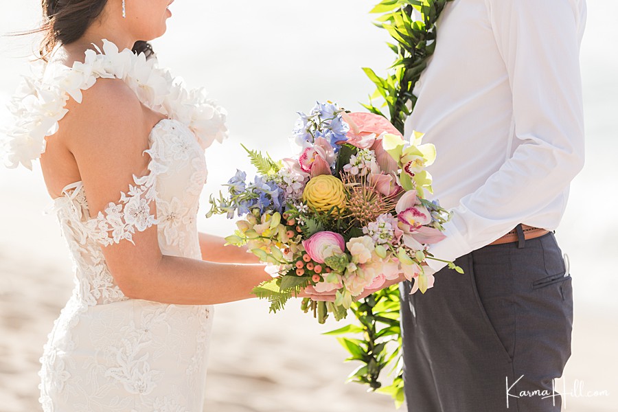 bride and groom hold hawaiian wedding bouquet as they read vows 