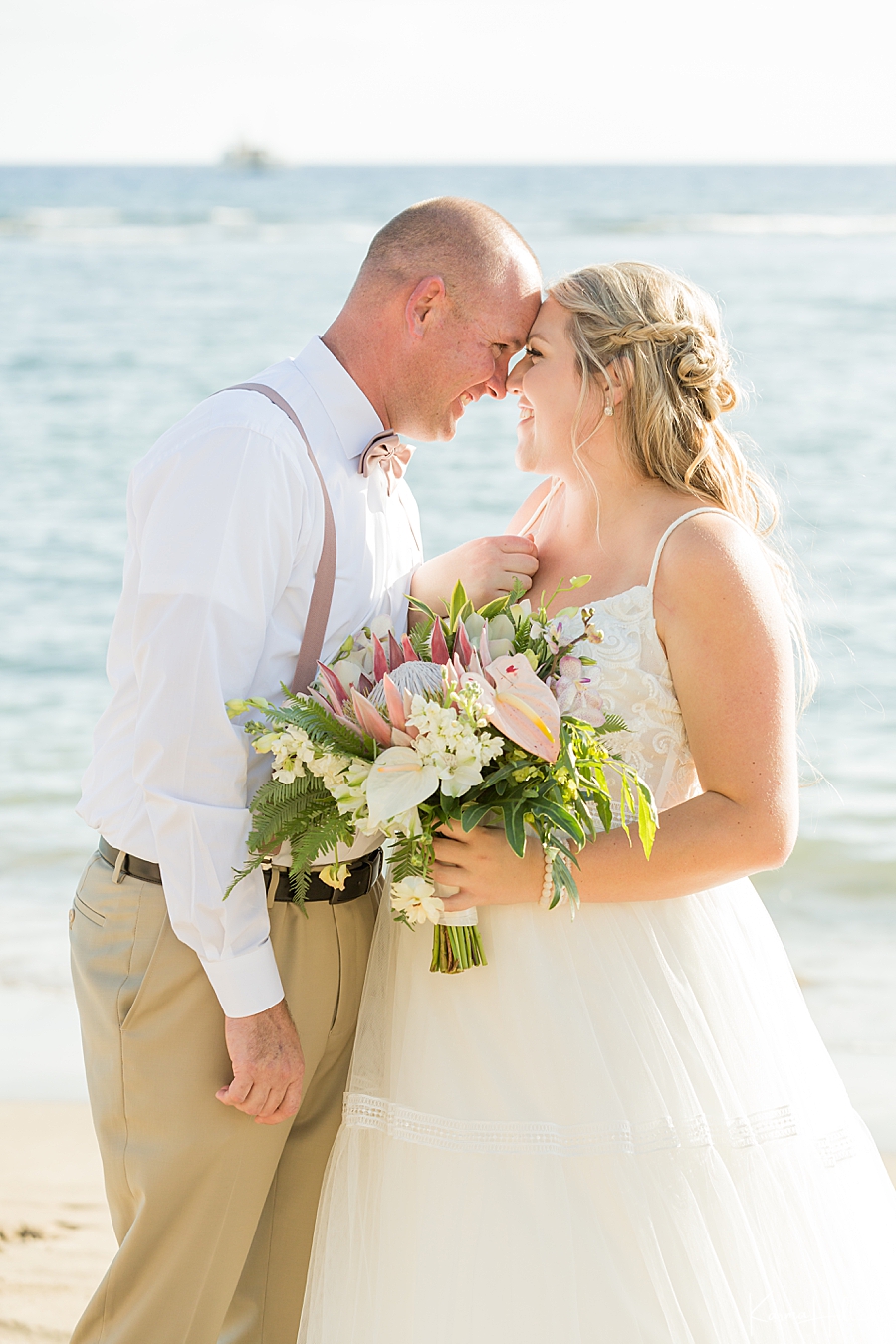cute couple touch foreheads during their maui wedding at lahaina shores 