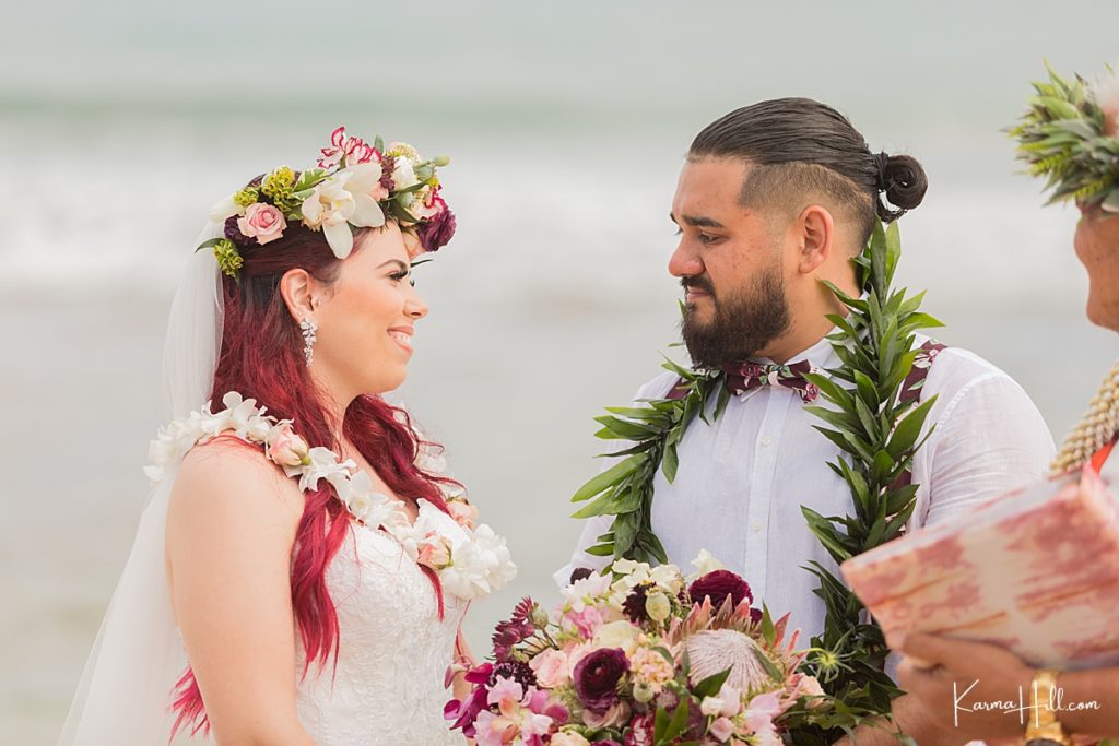 red haired bride smiles at groom during their beach wedding in hawaii 