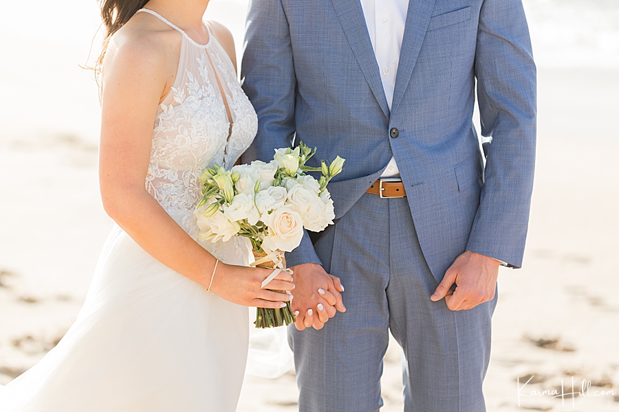 close up of couple eloping in maui holding hands with white rose bouquet 