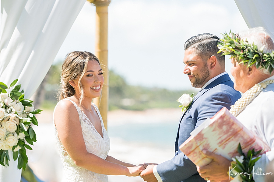 bride smiles at hawaiian minister as she holds hands with the groom 