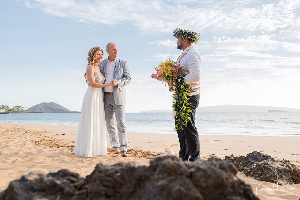 real hawaii wedding on a maui beach with lava rocks and ocean backdrops with a hawaiian minister in a haku lei 