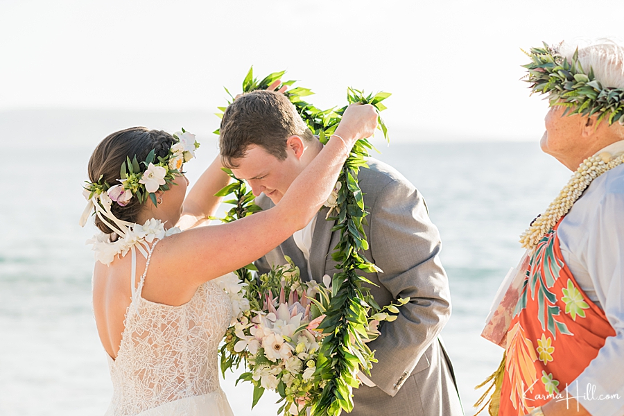 bride gives groom a maile lei during their hawaii beach wedding 