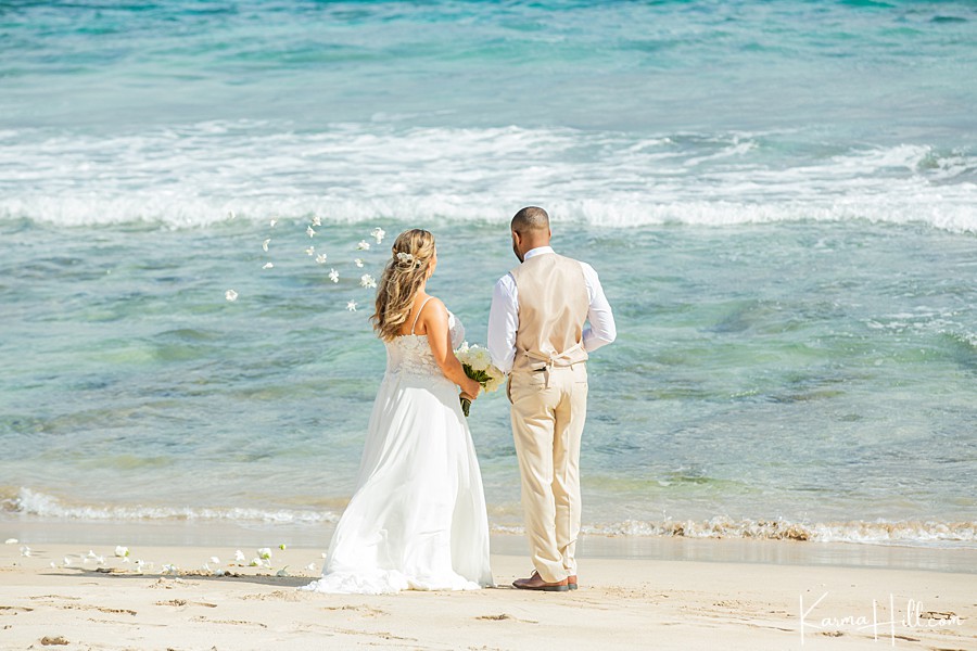 bride and groom send flowers into the ocean during their elopement 