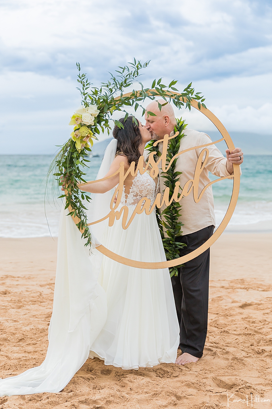 bride and groom posing with just mauid sign