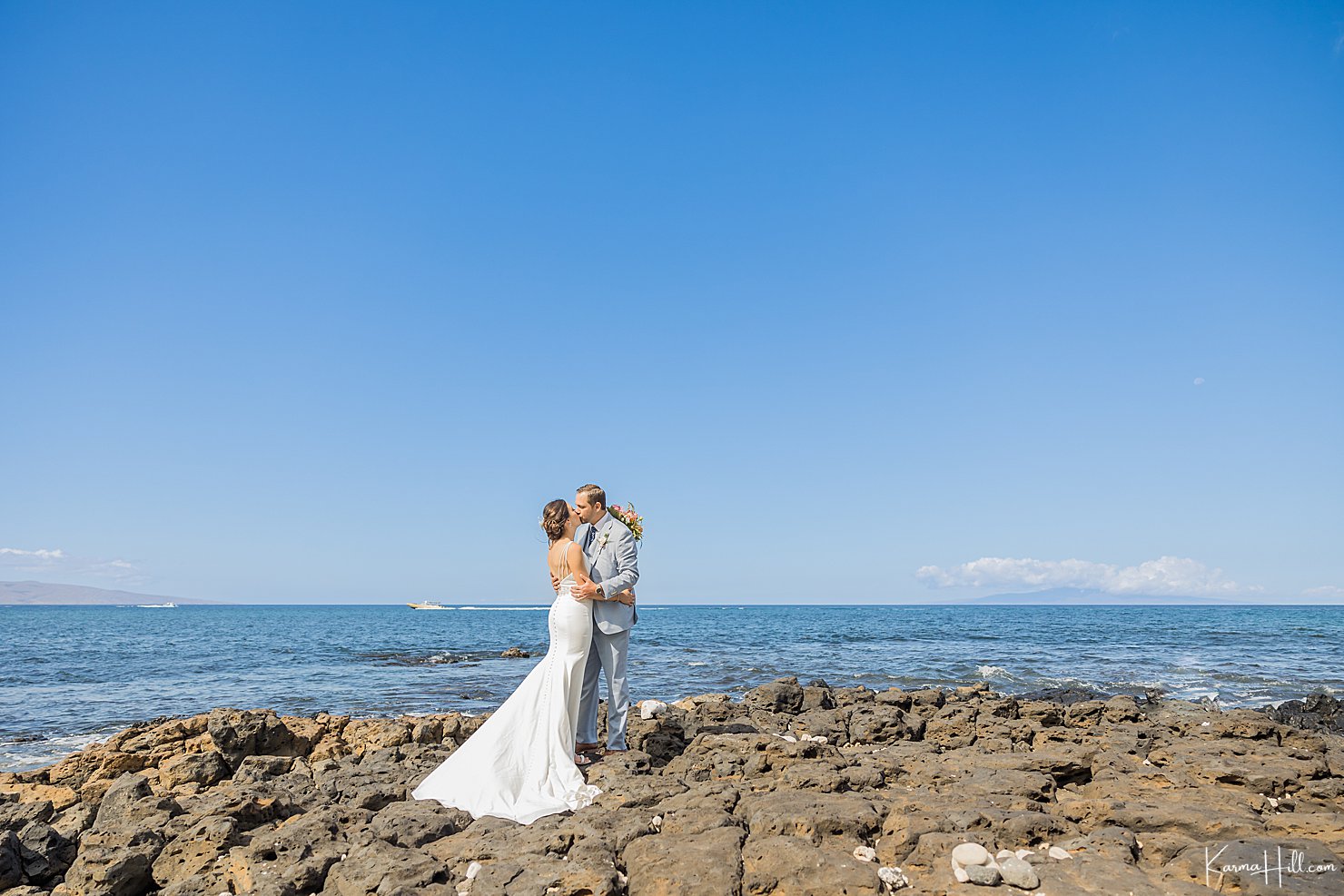 bride and groom kiss by ocean